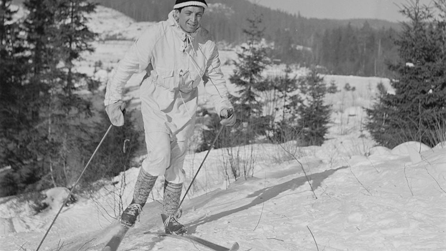 black and white photo of a man on wooden skis